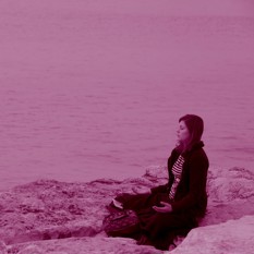 אישה יושבת על יד צוק ומתרגלת מדיטציה