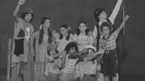 קבוצת ילדים עומדים ביחד כחלק מסצינת משחק בהצגה. 1.1.1976