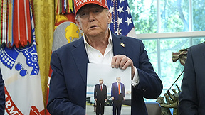 דונלד טראמפ בחדר הסגלגל, אוחז בתמונה שלו לצד נשיא רוסיה ולדימיר פוטין, אוגוסט 2025