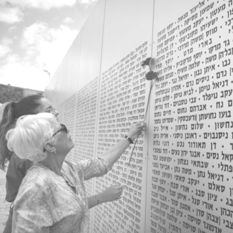 Israelis standing near wall with names of fallen I