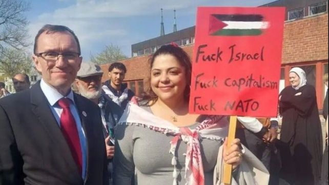 שר החוץ הנורווגי הצלם ליד שלט שמקלל את ישראל ונאטו ואותו אוחזת בת של מחבל