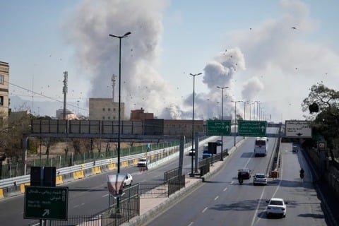 מכוניות נוסעות בכביש באיראן, כשברקע פטריות עשן