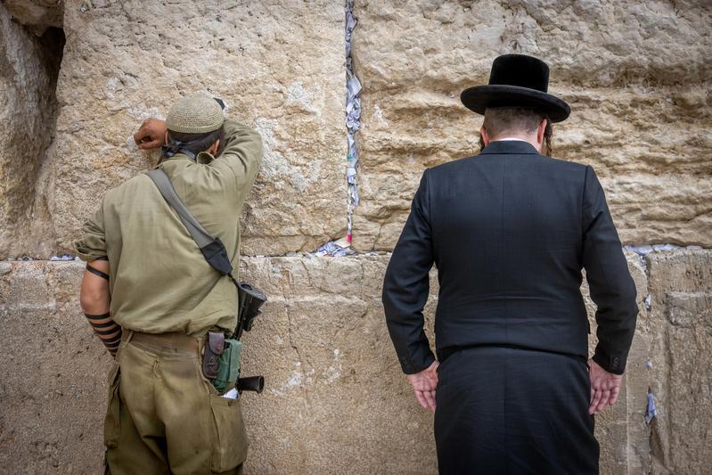 חייל וגבר חרדי מתפללים בכותל המערבי