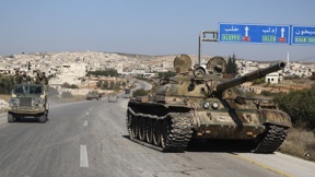 המורדים הסורים חולפים על פני טנק נטוש של משטר אסד
