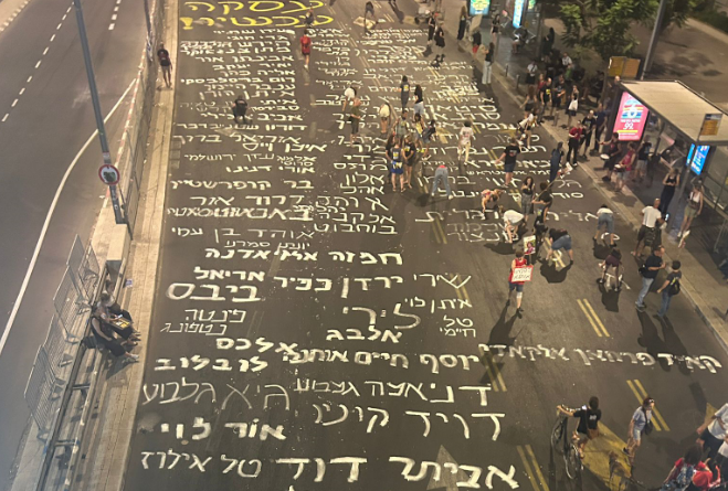 מפגינים למען שחרור החטופים כתבו את שמותיהם על הכביש מחוץ לקרייה בתל אביב, אוגוסט 2024