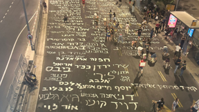 מפגינים למען שחרור החטופים כתבו את שמותיהם על הכביש מחוץ לקרייה בתל אביב, אוגוסט 2024