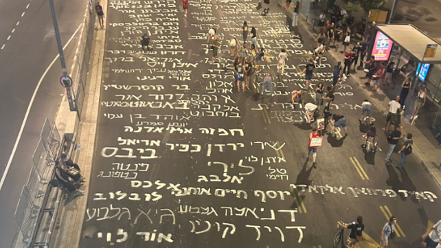 מפגינים למען שחרור החטופים כתבו את שמותיהם על הכביש מחוץ לקרייה בתל אביב, אוגוסט 2024