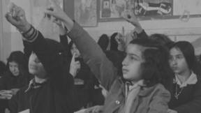 קבוצת בנות יושבות בכיתה ומצביעות. 1.1.1976