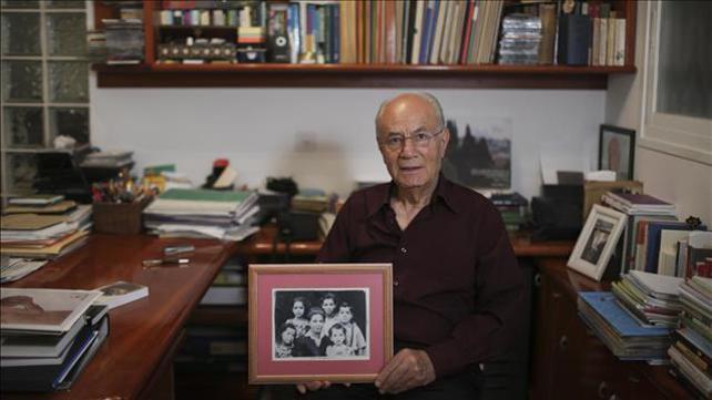 הסופר אלי עמיר מחזיק תמונה של משפחתו, 2014