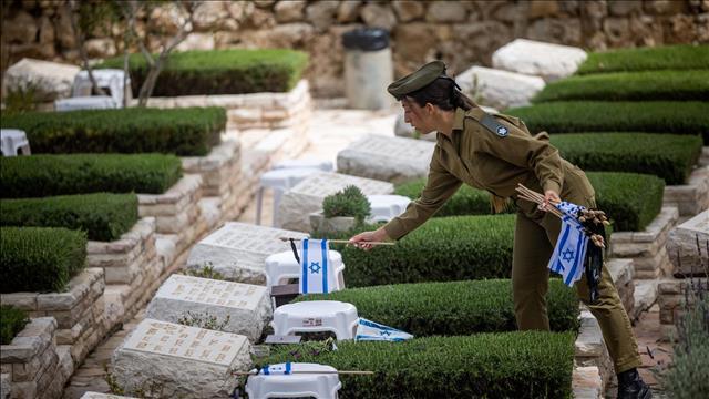חיילת מניחה דגל ישראל על קבר לקראת יום הזיכרון לחללי צה"ל 23.04.23