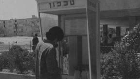 אדם משתמש בטלפון ציבורי מחודש. 23.4.1974